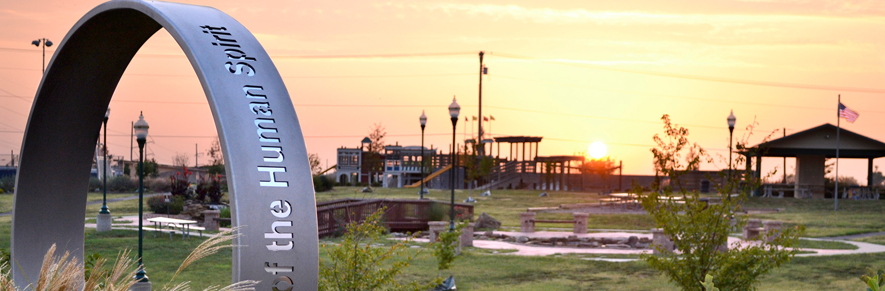 a field in missouri with buildings and a the human spirit ring sculpture