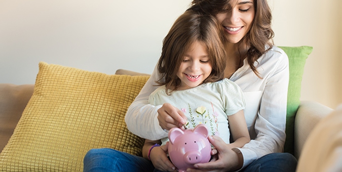 mother and daughter putting money in a piggy bank